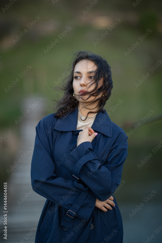 beautiful brunette european girl in blue trench coat at nature. Young lady with beautiful face.