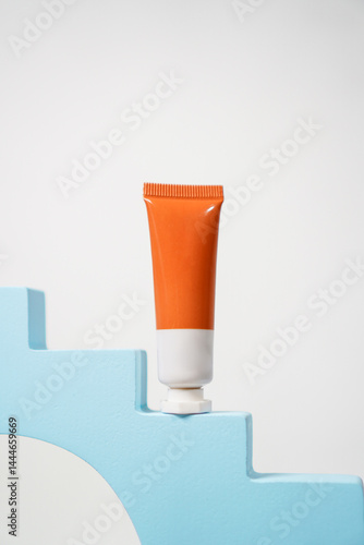 orange and white skincare tube packaging with blue staircase decoration podium on white background