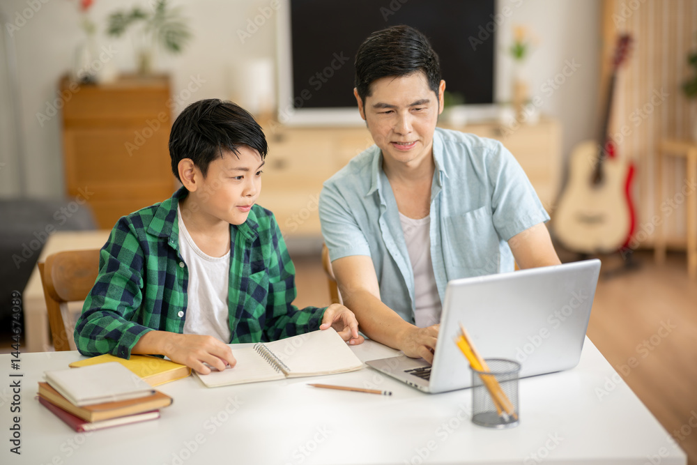 The father is teaching his son his homework with care at his home.
