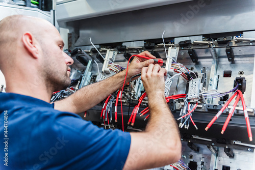 Electrician repairing electronics in an industrial machine plant
