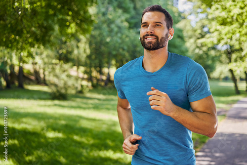 Handsome man running in park with earphones