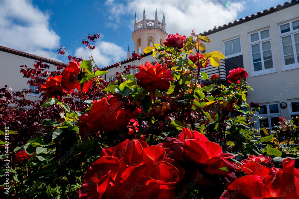 Vibrant Springtime colorful flowers and trees frame an old historic tower during a beautiful blue sky day