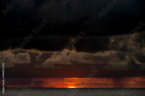 Obraz na płótnie Very moody and dramatic sky over the cloudy ocean horizon, with strong orange, sunbeams and traces of lingering storm cells w salonie