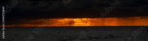 Obraz na płótnie Very moody and dramatic sky over the cloudy ocean horizon, with strong orange, sunbeams and traces of lingering storm cells w salonie