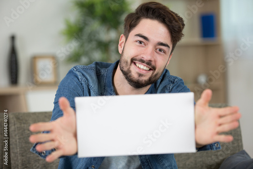 Obraz na płótnie young man in living-room holding a blank sign w salonie