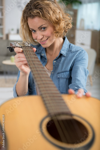 Obraz na płótnie woman checking the strings on her guitar w salonie
