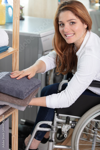 Obraz na płótnie young disabled woman on wheelchair tidying up clean laundry w salonie