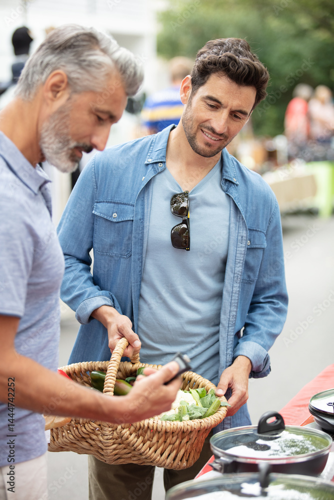 men looking at cookware on a street market