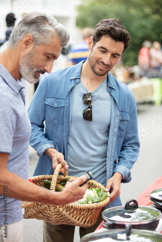 men looking at cookware on a street market