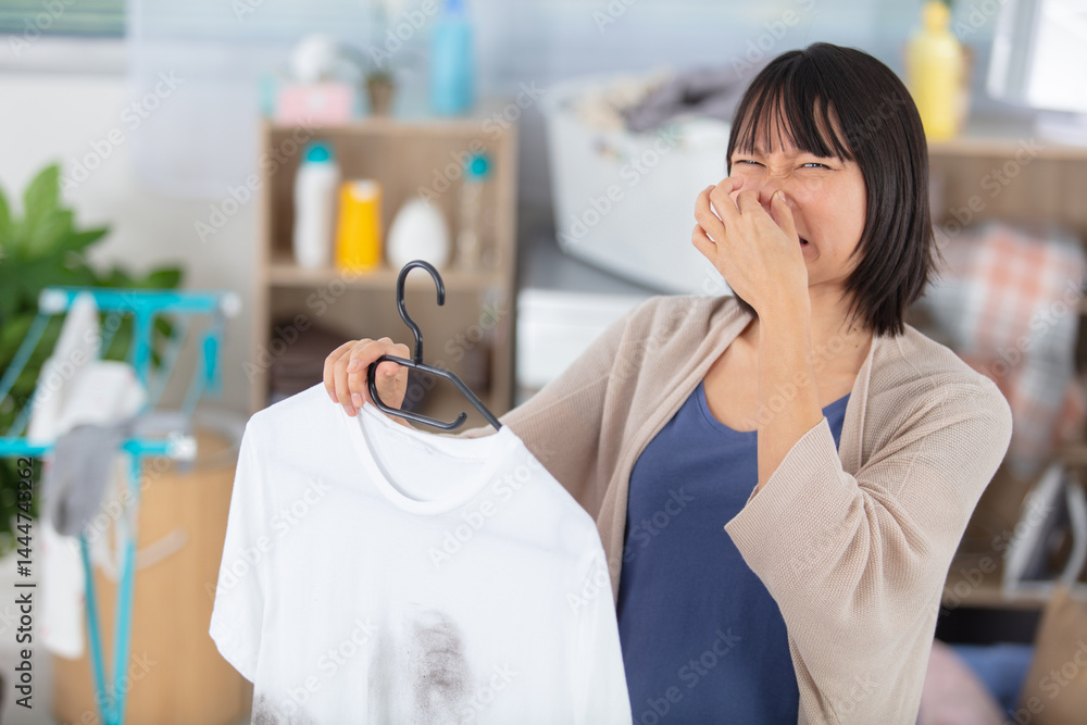 woman bad smell gesture while holding shirt