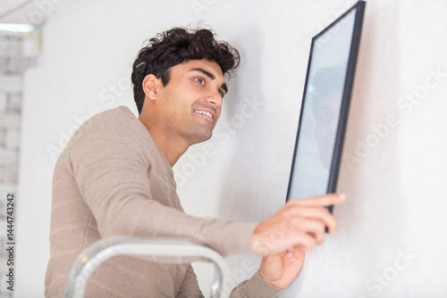 cheerful young men hanging a picture on the wall