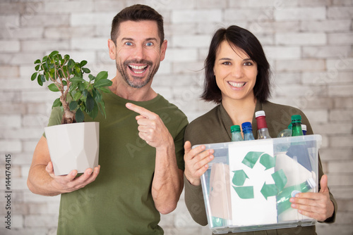 happy couple hold a plastic container and a small tree