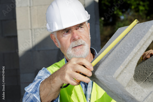 construction worker is measuring a cement block