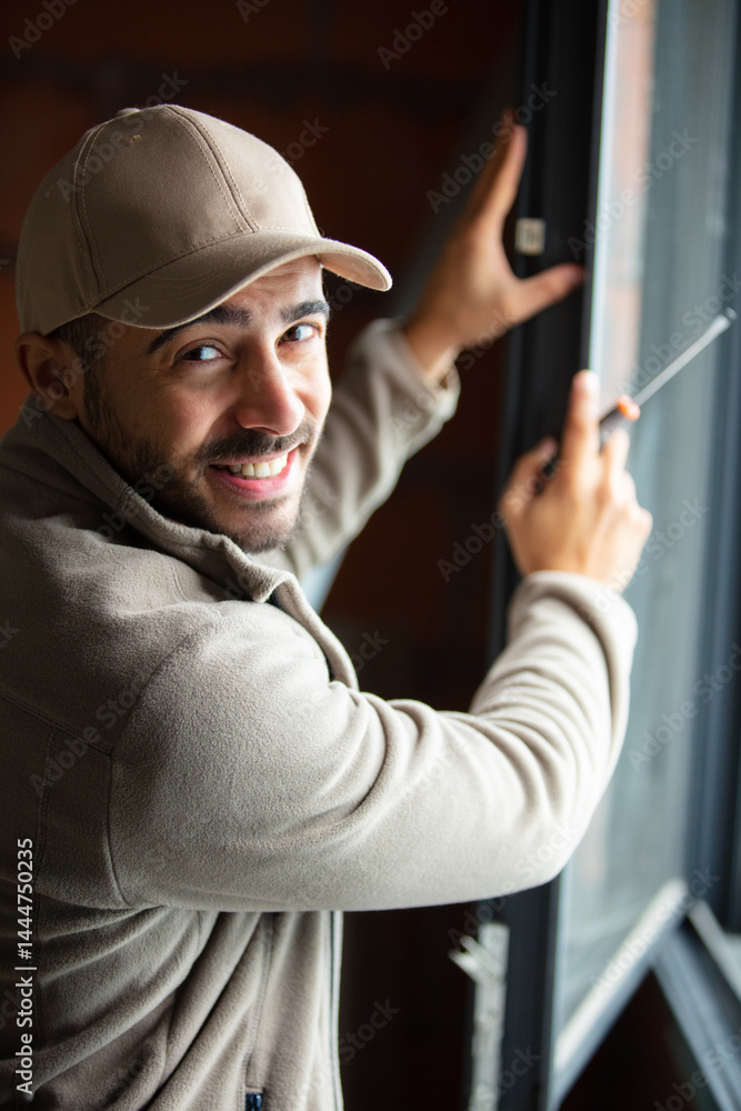 builder man using a screwdriver to install window