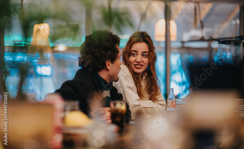 Two friends share a pleasant conversation at a cozy bar with a warm ambiance. The atmosphere is inviting and relaxed, perfect for catching up and enjoying good company over refreshments.