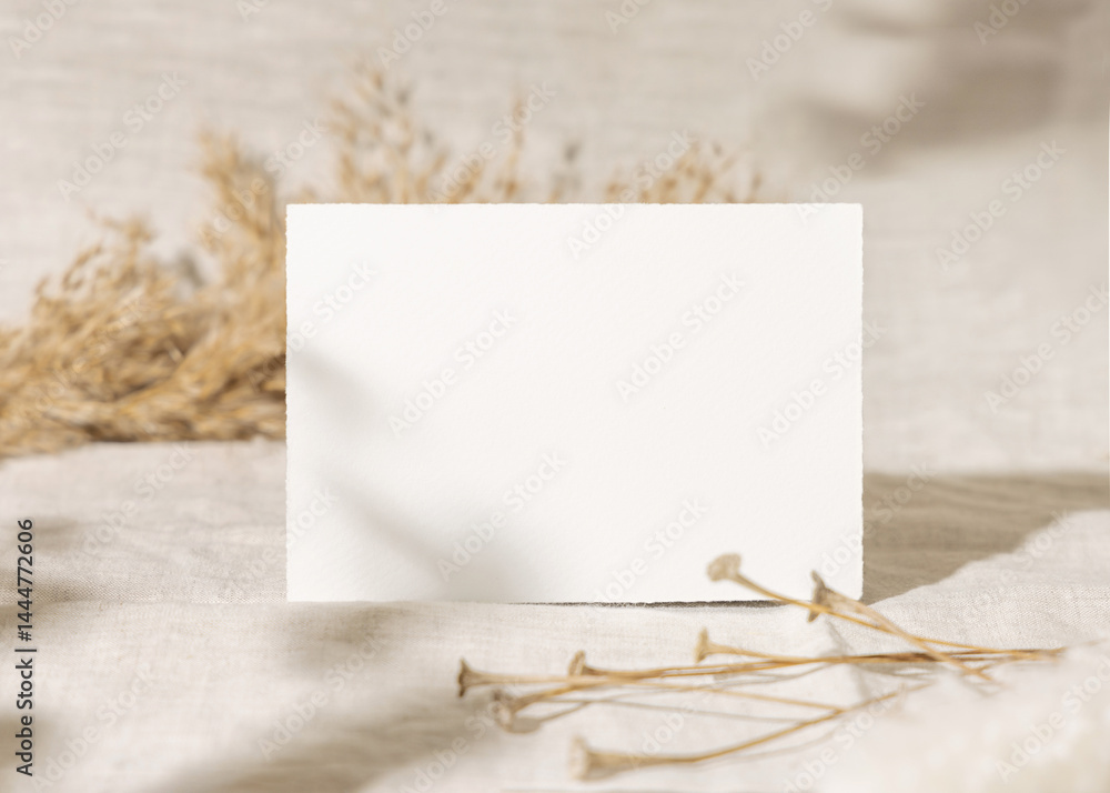 Blank card near dry beige pampas grass on linen closeup, mockup. Bohemian wedding stationery