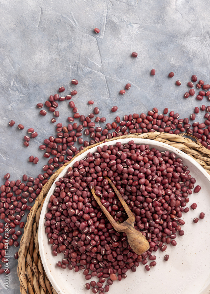 Plate full of dried red azuki beans with a wooden scoop top view. East Asian legumes, vegetarian food