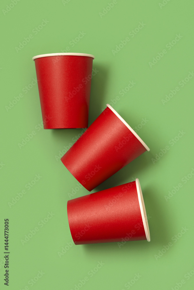 Disposable red paper cups on a green top view, mockup. No plastic and sustainable Christmas