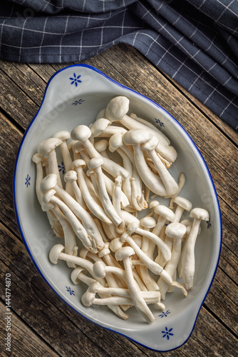 Obraz na płótnie Raw white shimeji mushrooms in bowl on wooden table. Top view. w salonie