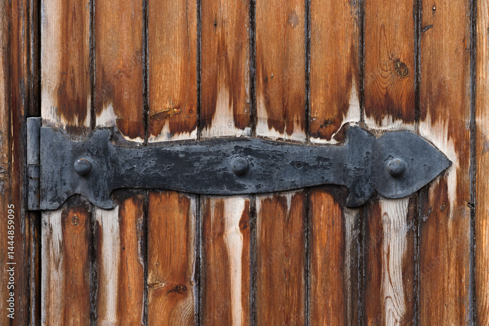 Old door with an ornate black wrought iron hinge