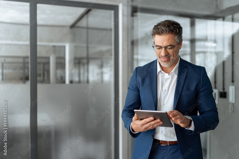 © Stock 4 You - Executive man in suit working using computer for financial business banking work. Smiling senior mature Indian or Latin entrepreneur businessman looking at digital tablet screen in office. Copy space