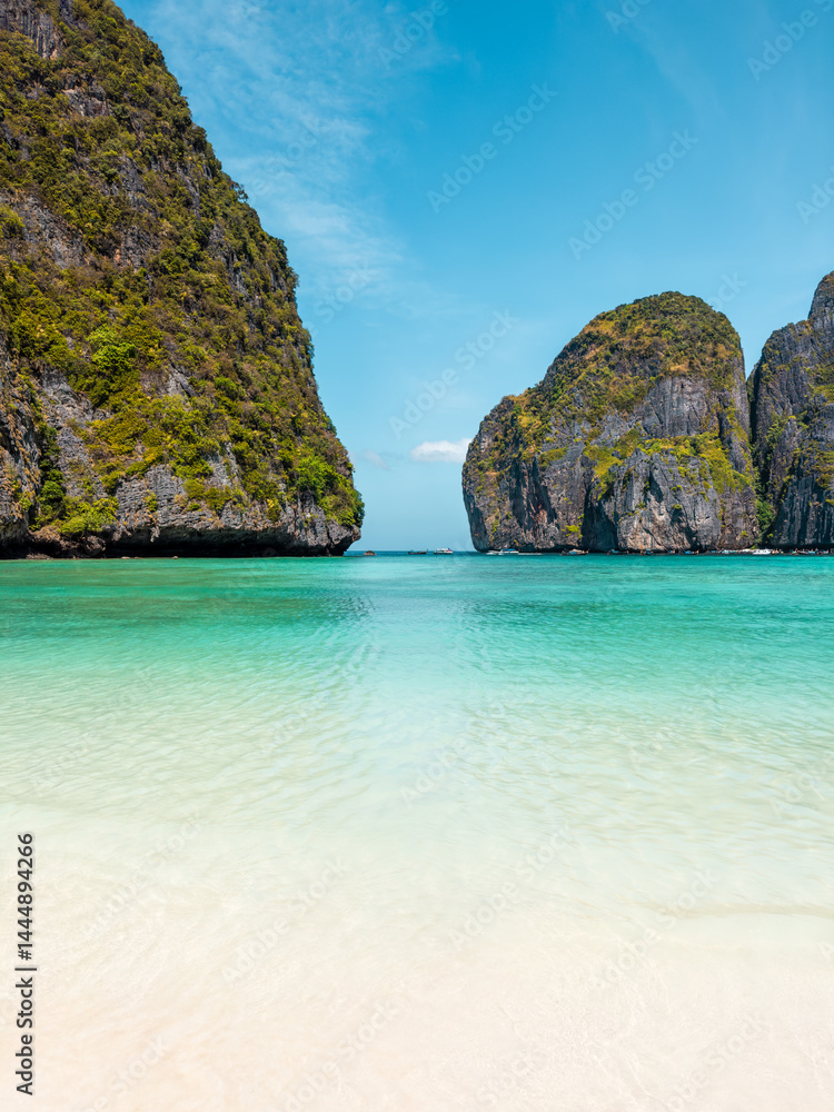 Idyllic beach perspective of Maya Bay with shallow turquoise sea and towering cliffs, ideal for exotic travel promotions, vacation destinations, and tropical paradise nature photography themes.
