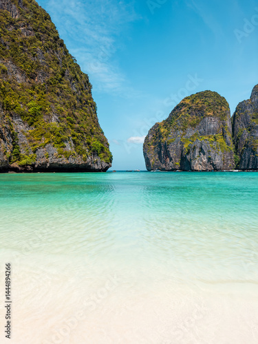 Obraz na płótnie Idyllic beach perspective of Maya Bay with shallow turquoise sea and towering cliffs, ideal for exotic travel promotions, vacation destinations, and tropical paradise nature photography themes. w salonie