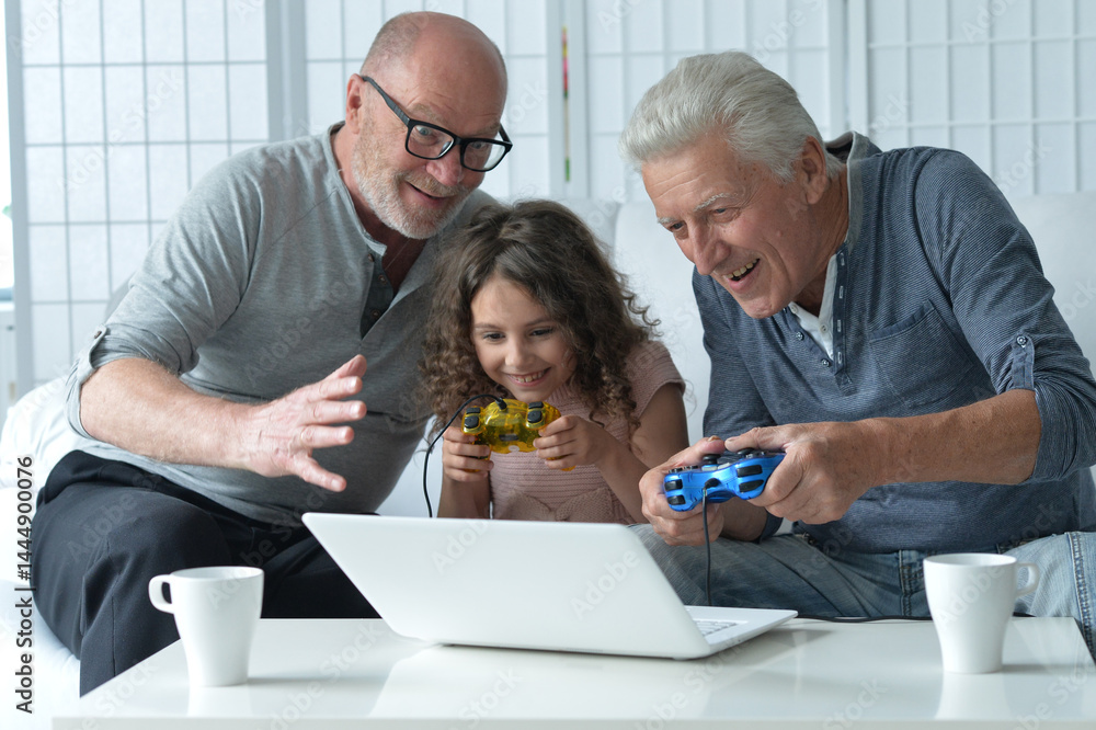 Two old men with granddaughter playing on laptop