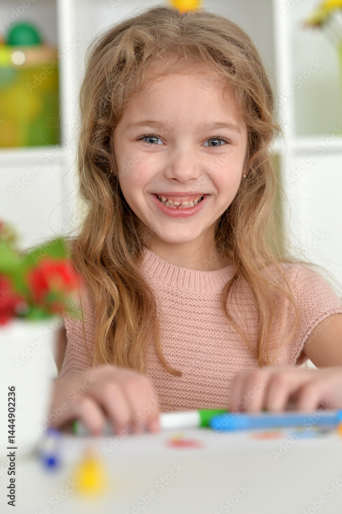 cute girl in the nursery draws at the table