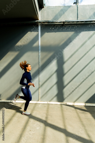Obraz na płótnie Dynamic urban runner embracing morning sunlight through geometric shadows in a modern space w salonie