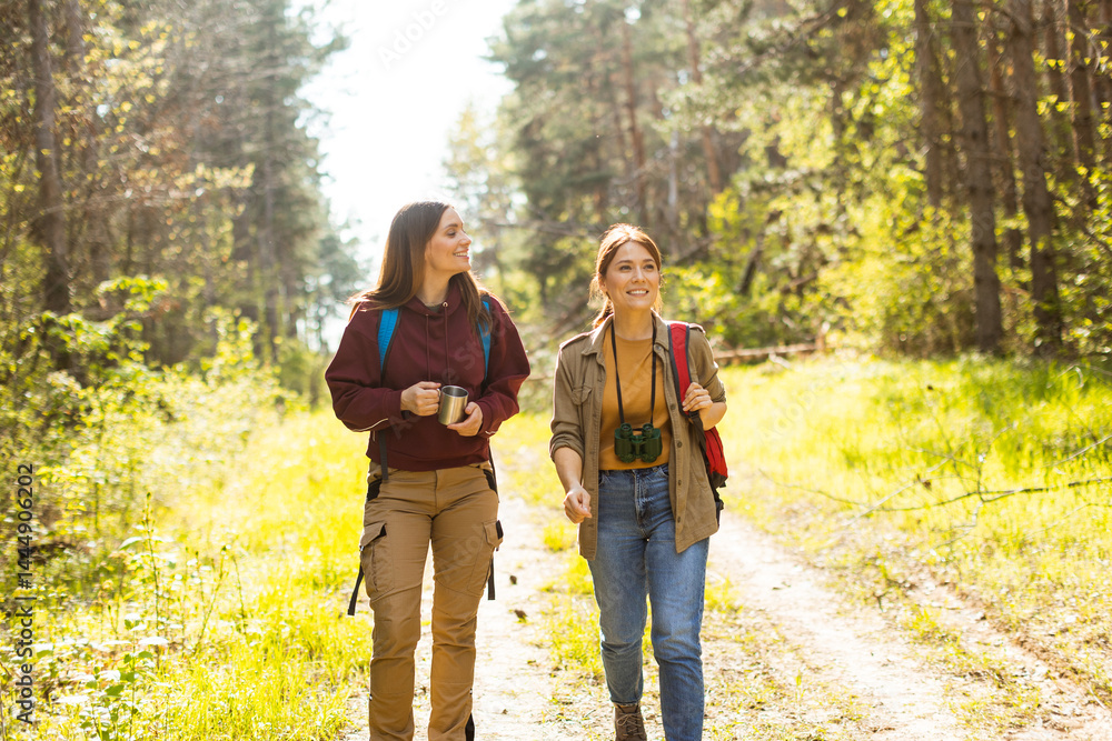 Enjoying a sunny hike through the serene forest with cheerful friends connecting with nature