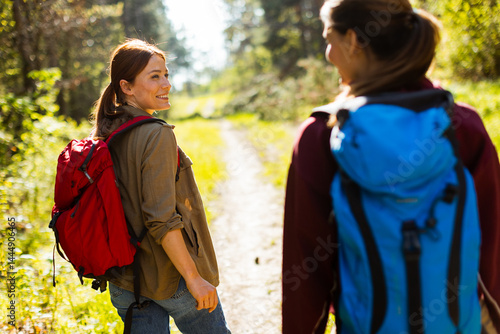 Obraz na płótnie Two friends enjoy a sunny hike through a vibrant forest trail, sharing smiles and laughter amidst nature's beauty w salonie