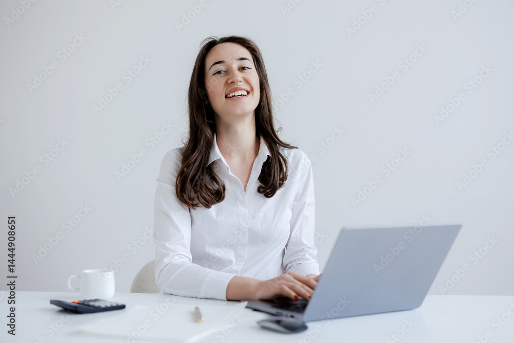 Smiling woman working at a laptop in a bright, modern office space during the day