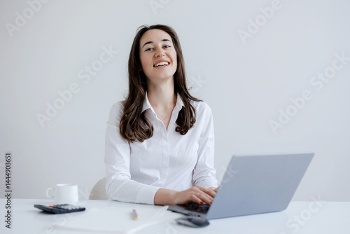 Obraz na płótnie Smiling woman working at a laptop in a bright, modern office space during the day w salonie