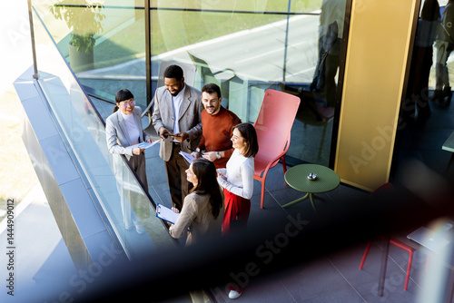 Group of professionals collaborating on project details in modern office space during sunny day