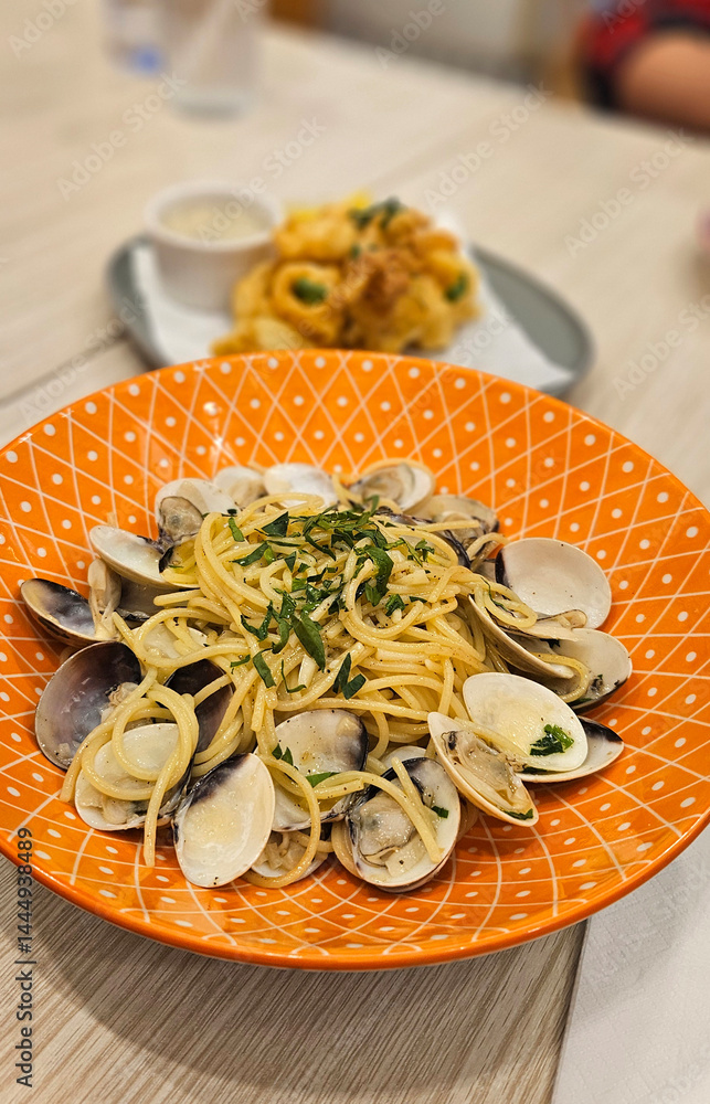 Spaghetti vongole spaghetti with clams & mussels serving on yellow plate