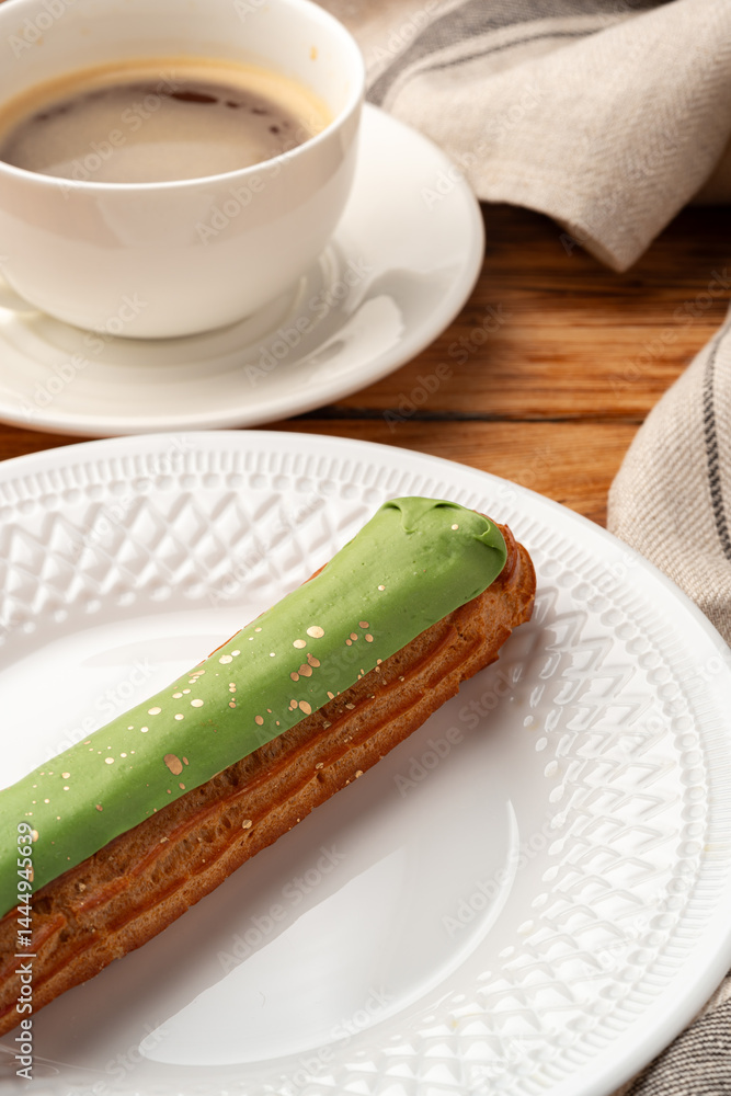 Delicious pastry with green icing served beside a cup of coffee on a wooden table during a cozy afternoon