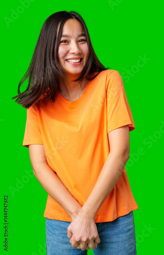 Obraz na płótnie Smiling young woman enjoying herself in a vibrant orange shirt against a bright green background w salonie
