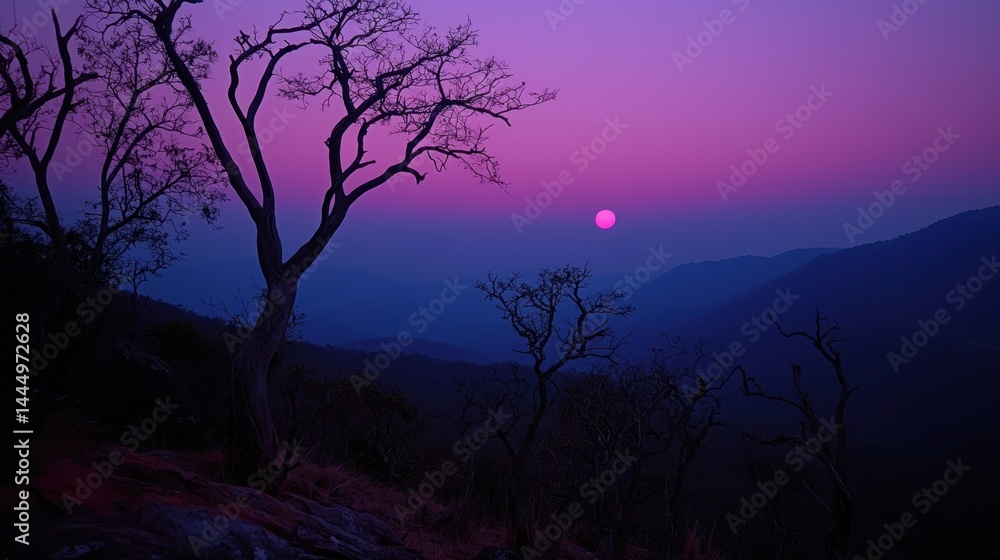 Fototapeta premium Beautiful purple and blue sunset over mountainous landscape with trees