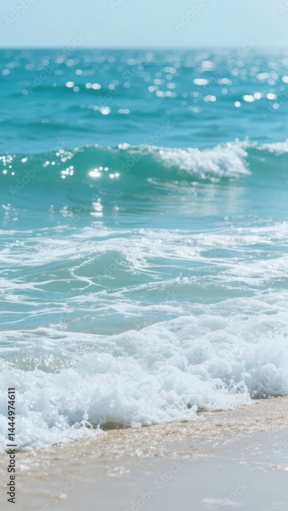 Fototapeta premium Waves crashing on a sandy beach with clear blue sky