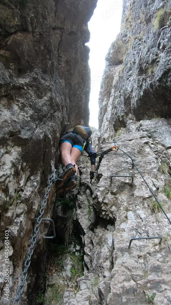 Descending into a narrow cleft, a climber pauses to adjust his harness before entering Lecco’s secluded Ferrata Centenario rock chasm. Descending into a narrow cleft, a climber pauses to adjust his harness before entering Lecco’s secluded Ferrata Centenario rock chasm.