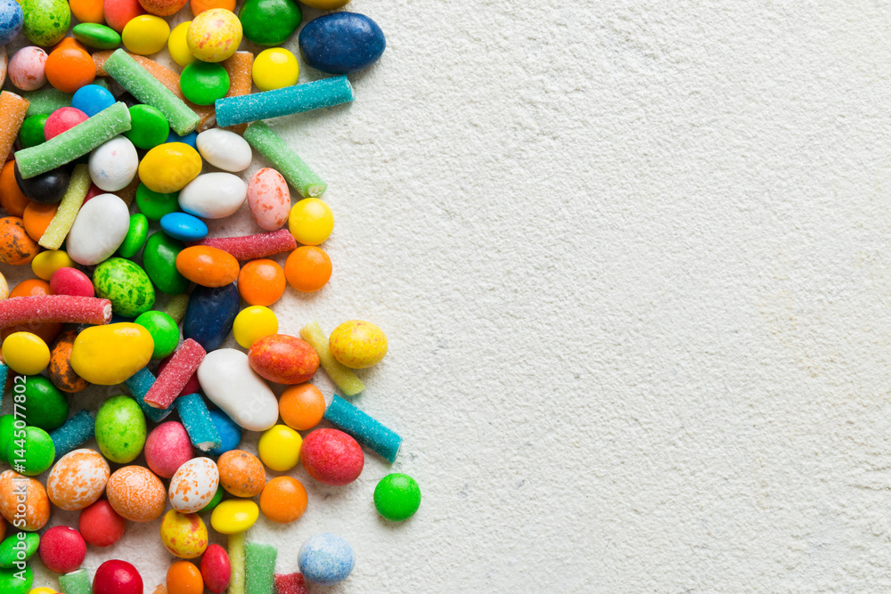 Obraz premium Mixed collection of colorful candy, on colored background. Flat lay, top view. frame of colorful chocolate coated candy