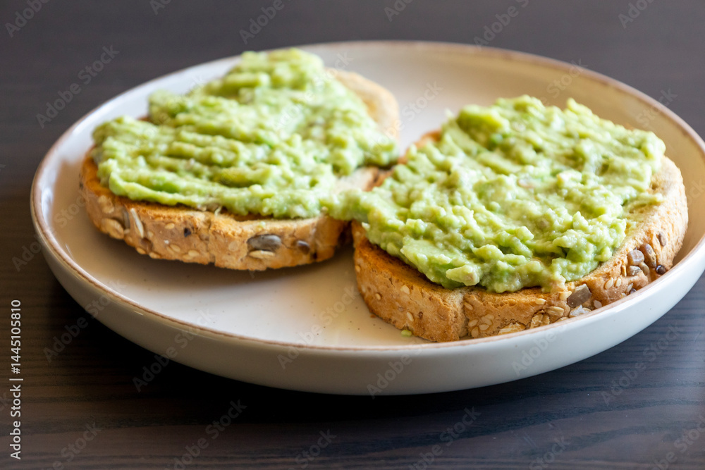 Close-up of two slices of toasted bread topped with a creamy avocado spread. A simple and healthy breakfast Close-up of two slices of toasted bread topped with a creamy avocado spread. A simple and healthy breakfast