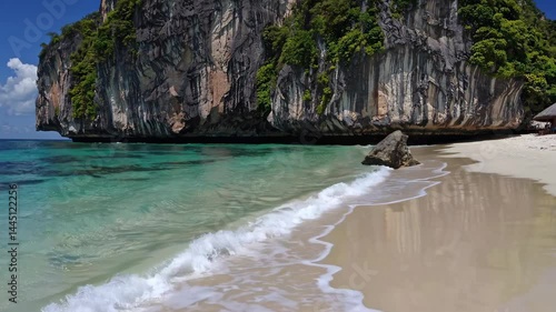 Tropical white sandy beach with turquoise waters and limestone cliffs
