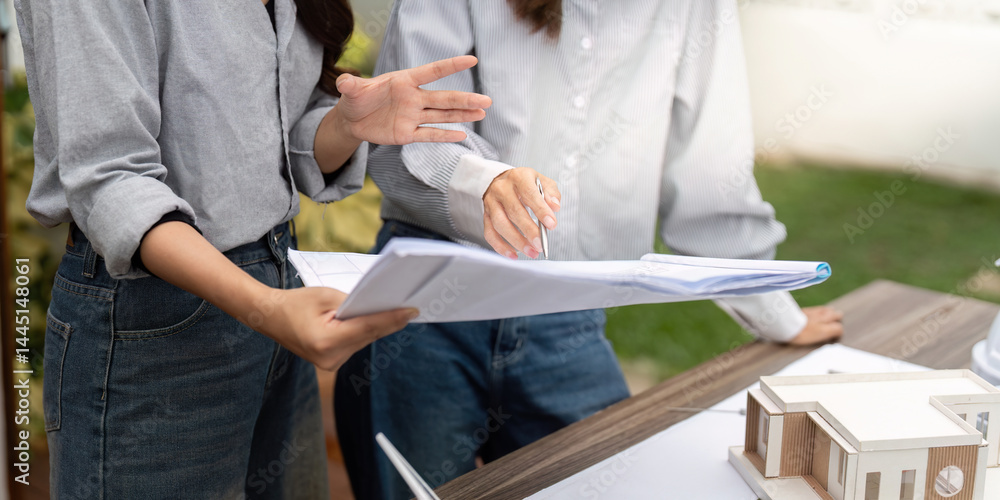 Obraz premium Innovative Sustainable Design. Architects analyzing building plans with a focus on eco-friendly solutions.