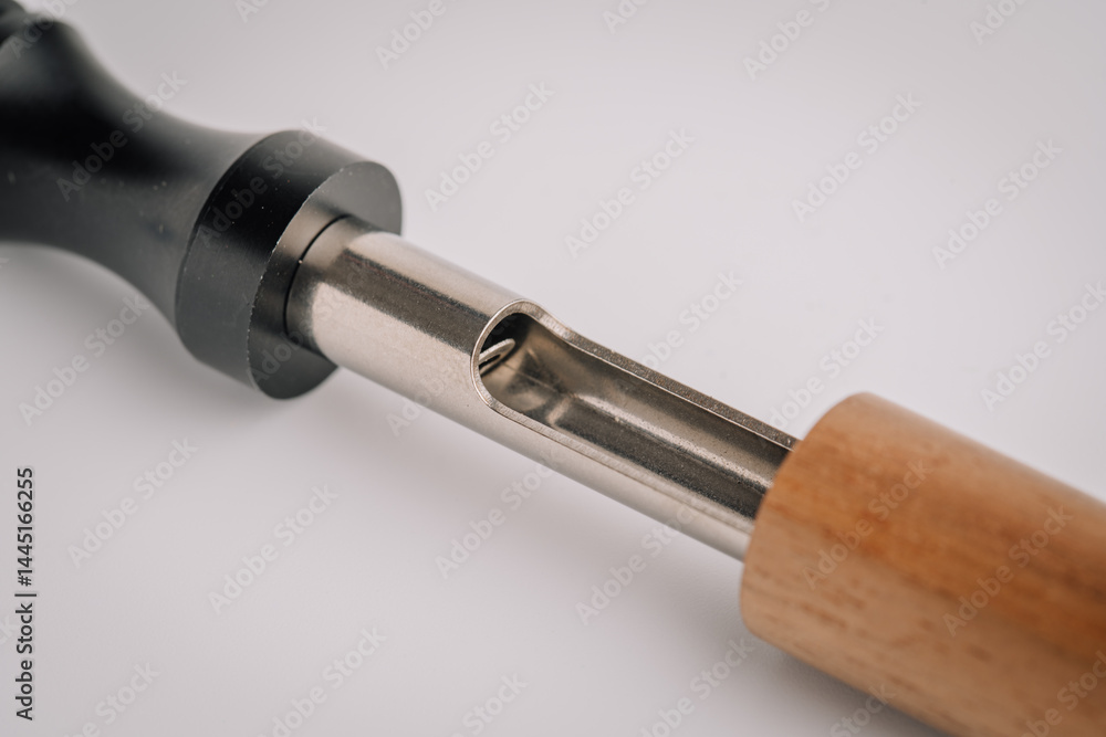 Close-up of a partially disassembled vape device showing the inner metal chamber between a black mouthpiece and a wooden handle, on a white background.. Close-up of a partially disassembled vape device showing the inner metal chamber between a black mouthpiece and a wooden handle, on a white background..