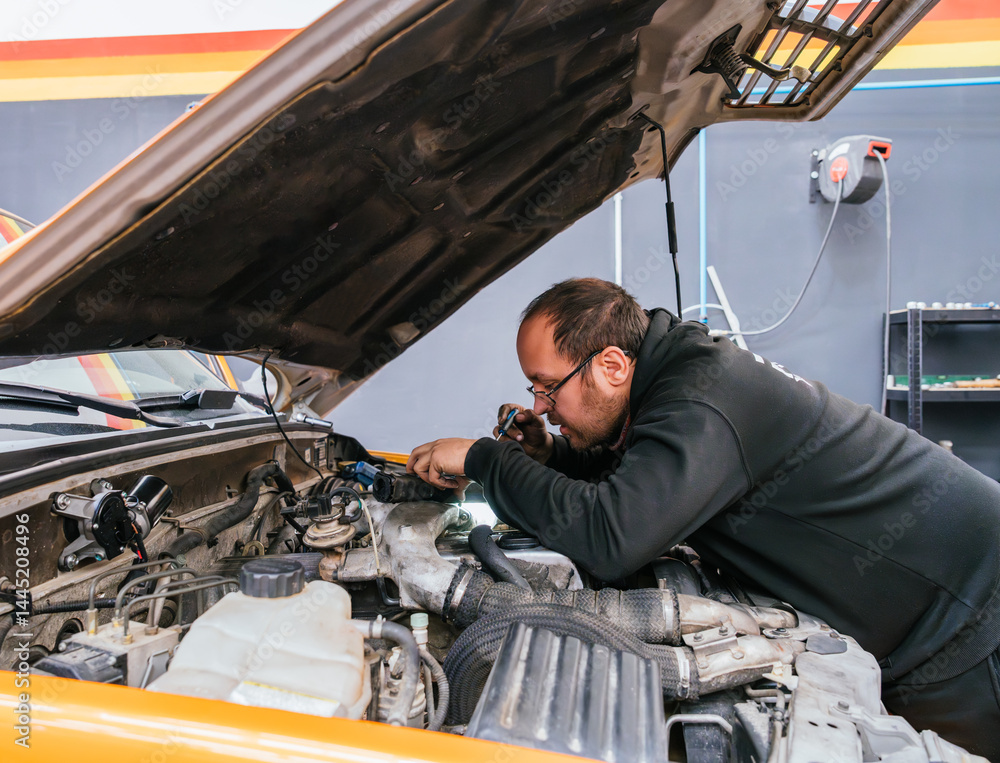 Mechanic using screwdriver and flashlight to repair car electrical system in workshop Mechanic using screwdriver and flashlight to repair car electrical system in workshop