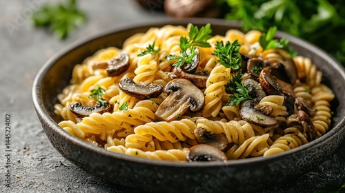 Delicious spiral pasta with saut?ed mushrooms fresh parsley in a rustic black bowl on a textured gray surface for a hearty home-cooked Italian meal