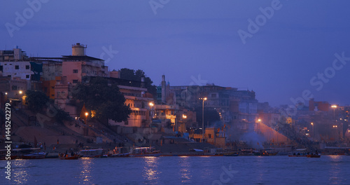 Obraz na płótnie Varanasi, Uttar Pradesh, India. People walking on steps on Shivala Ghat and floating in boats near Dandi Ghat. Evening time. Camera moving along riverbank embankment. Cinematic View from river w salonie