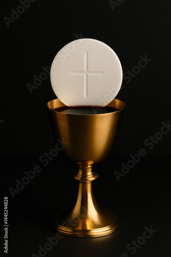 Communion Host and Golden Chalice on Dark Background